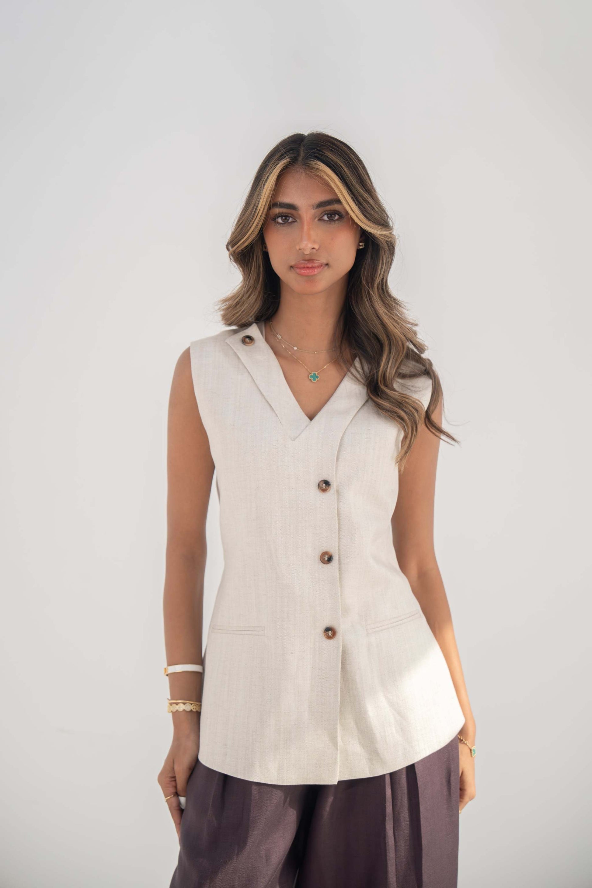 Beige sleeveless twill linen blend vest with V-neck, front buttons, side slits, and removable collar flap.