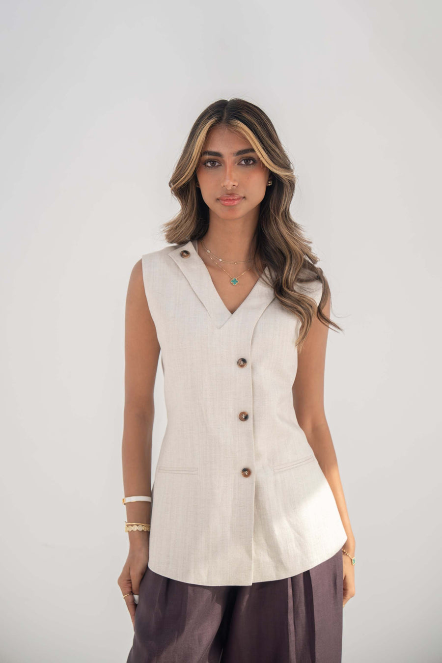 Beige sleeveless twill linen blend vest with V-neck, front buttons, side slits, and removable collar flap.