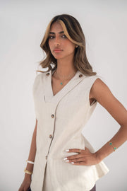 Beige sleeveless Madeleine Vest in twill linen blend with V-neck, front buttons, curved hem, side slits, and removable collar flap.