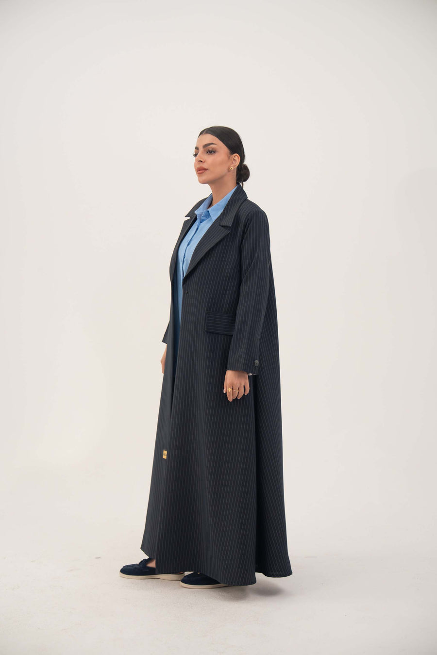 Woman wearing Zanira premium crepe blend open-front navy blazer abaya with white pinstripes and shoulder pads.