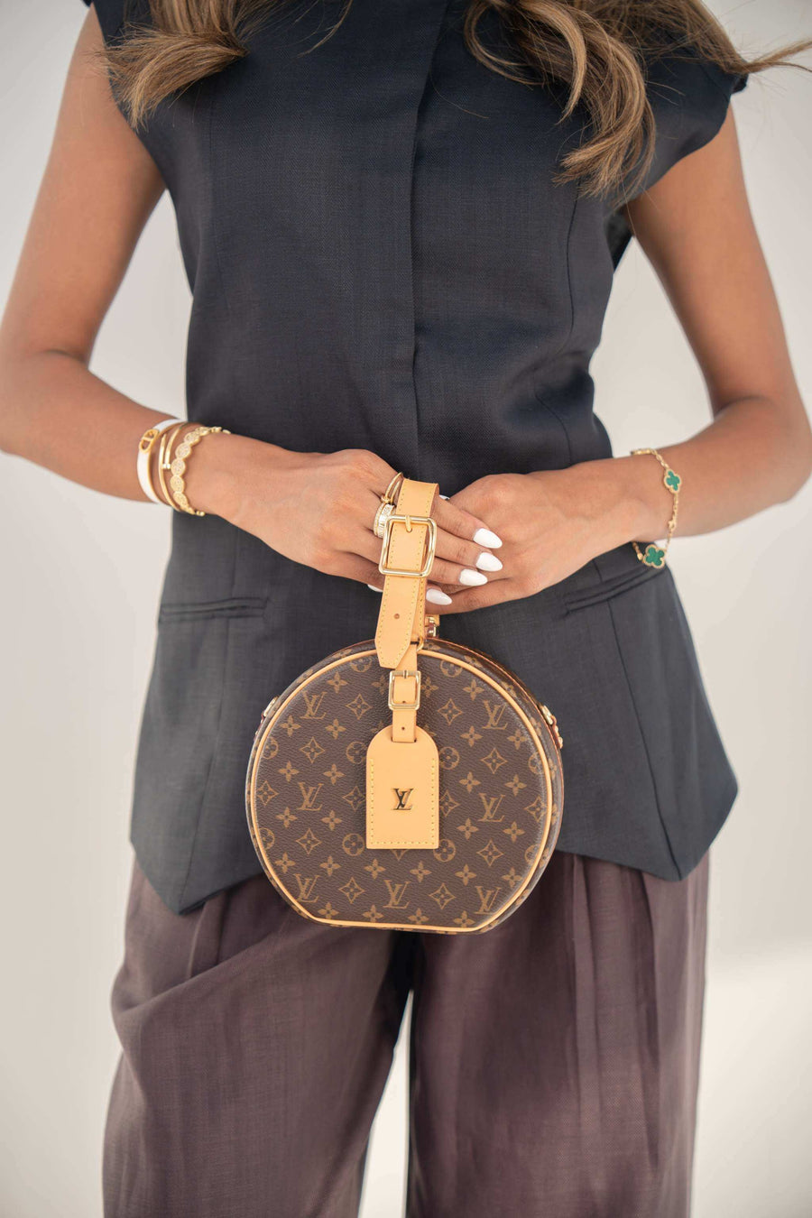 Navy twill linen blend blouse with hidden front buttons and structured cut, styled with brown pants and round designer handbag.