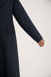 Deep navy open-front blazer with white pinstripes, wide lapel, shoulder pads, decorative pockets, and buttoned cuffs.
