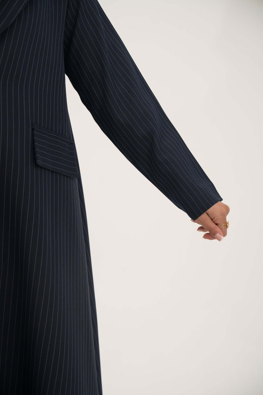 Deep navy open-front blazer with white pinstripes, wide lapel, shoulder pads, decorative pockets, and buttoned cuffs.