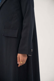 Deep navy crepe blazer with white pinstripes, wide lapel, shoulder pads, decorative pockets, and buttoned cuffs.
