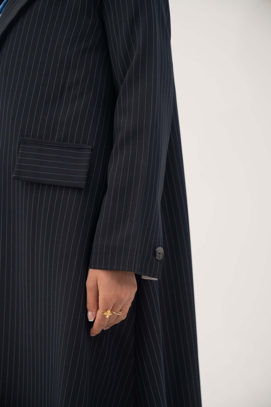 Deep navy crepe blazer with white pinstripes, wide lapel, shoulder pads, decorative pockets, and buttoned cuffs.