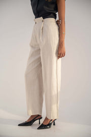 Beige high-waisted Madeleine Pants in twill linen blend with relaxed straight-leg fit, styled with black top and heels.