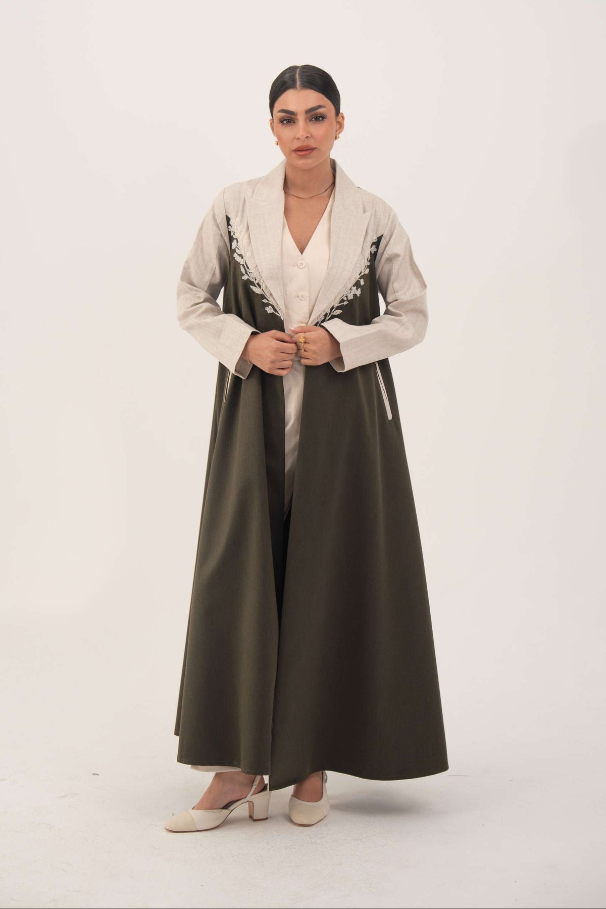 woman wearing olive green abaya crafted from soft twill with beige linen panels and white leaf embroidery