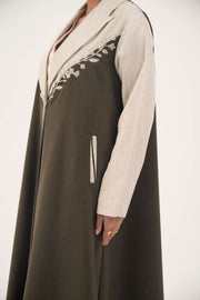 Deep olive green abaya with beige linen panels, white leaf embroidery, notched lapels, full-length cut, and beige-trimmed side slit pockets.
