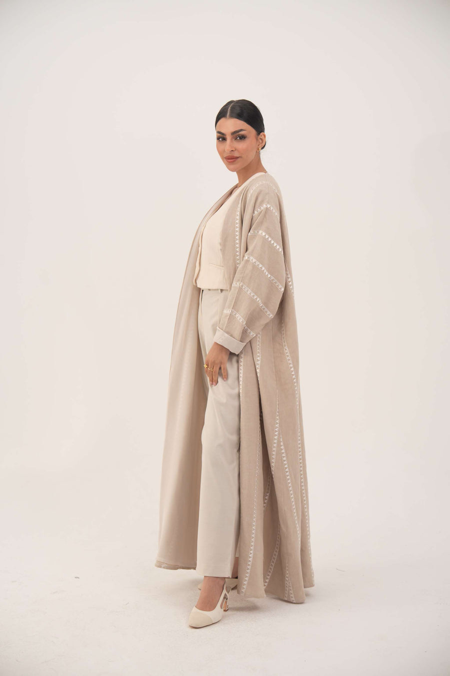 woman wearing creamy beige linen airy abaya with tonal embroidery and chiffon cuffs, open front design, classic bisht silhouette
