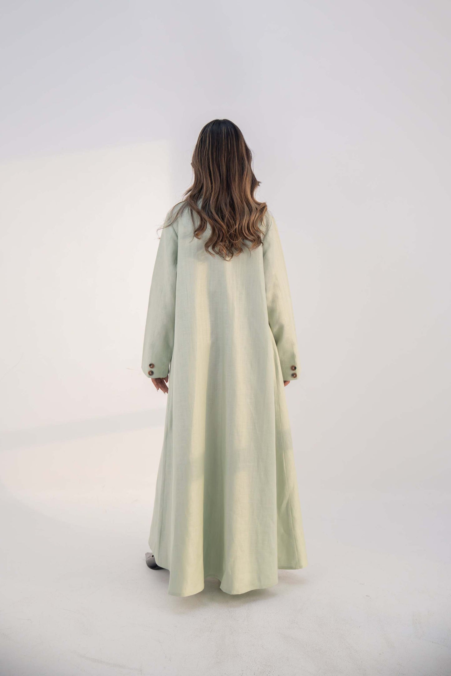 Back view of a woman wearing a mint fudge tailored blazer abaya with structured lapels and button details