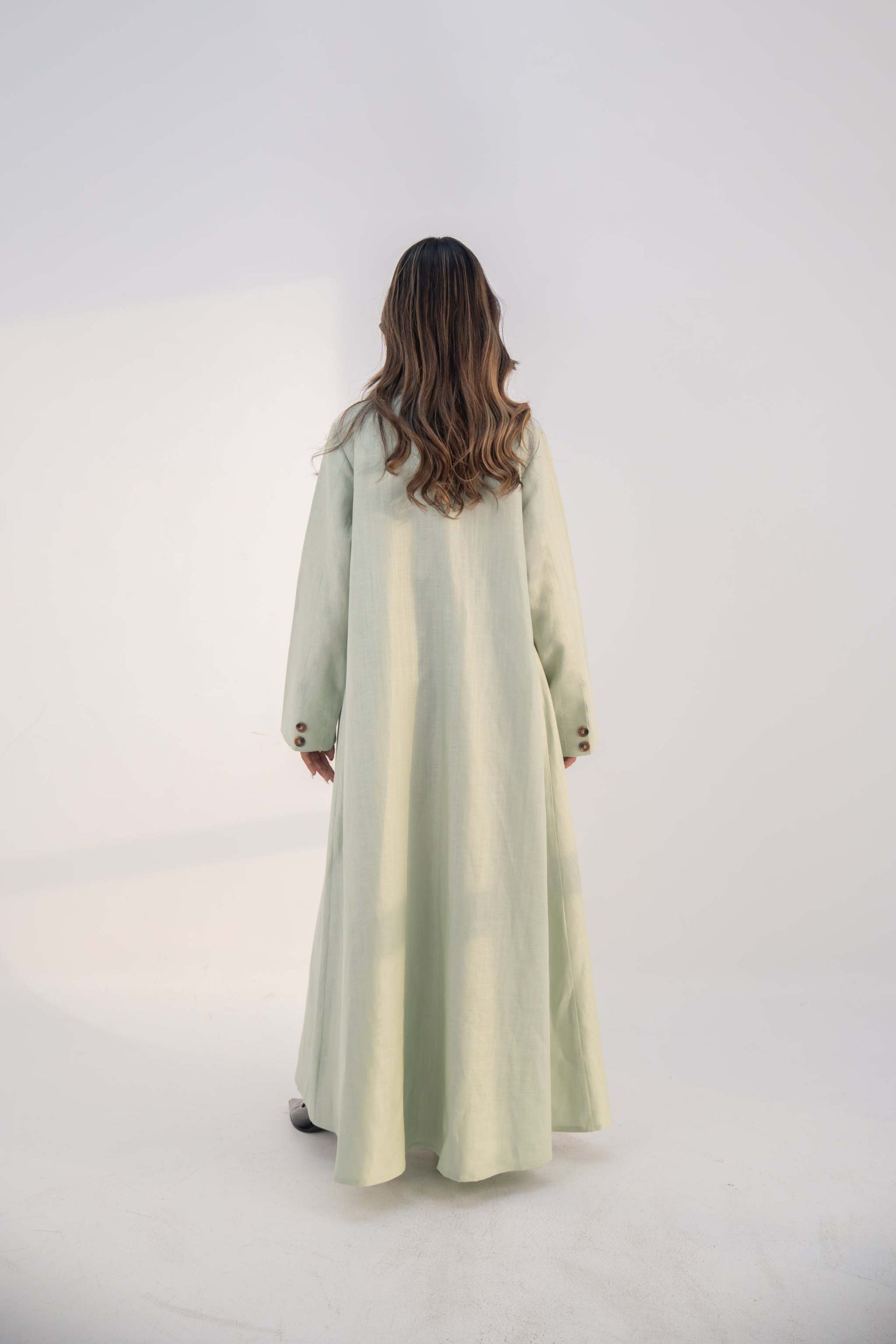 Back view of a woman wearing a mint fudge tailored blazer abaya with structured lapels and button details