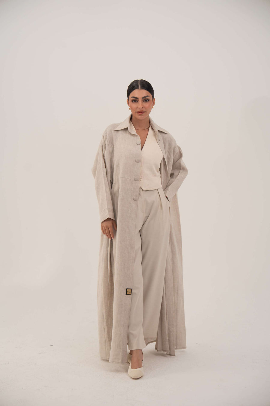 Sandora soft beige linen abaya with classic shirt collar and fabric-covered buttons.