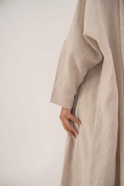 Sandora soft beige linen abaya with classic shirt collar and fabric-covered buttons.