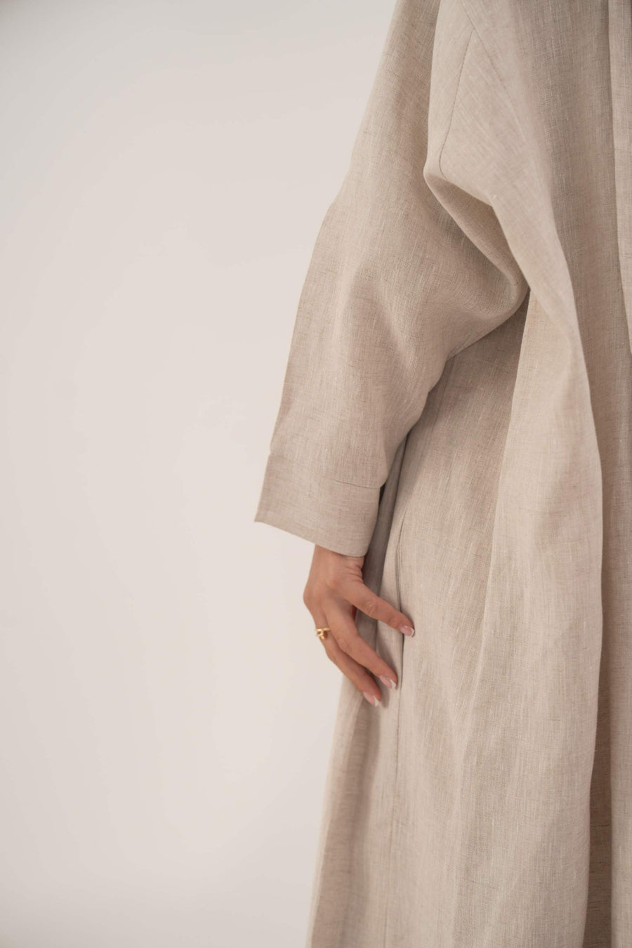 Sandora soft beige linen abaya with classic shirt collar and fabric-covered buttons.