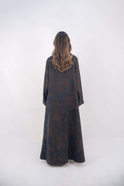 Back view of a navy jacquard silk abaya with subtle brown floral patterns and wide sleeves on a standing woman