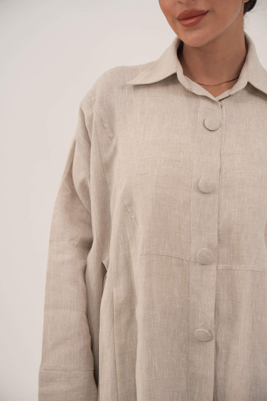 Sandora soft beige linen abaya with classic shirt collar and fabric-covered buttons.