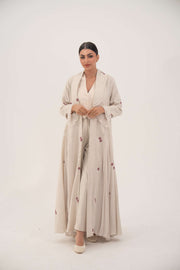 Woman wearing elegant natural beige linen abaya with burgundy floral embroidery and chiffon pleats.