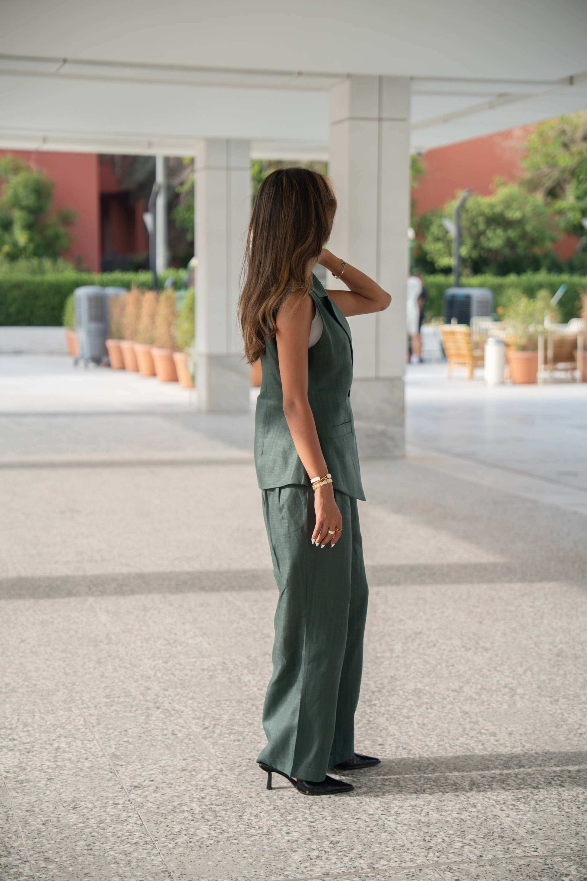 Woman wearing dark green wide-leg linen pants and matching sleeveless top in an outdoor urban setting