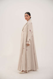 Natural beige linen abaya with burgundy floral embroidery, soft chiffon pleats, and shawl collar.