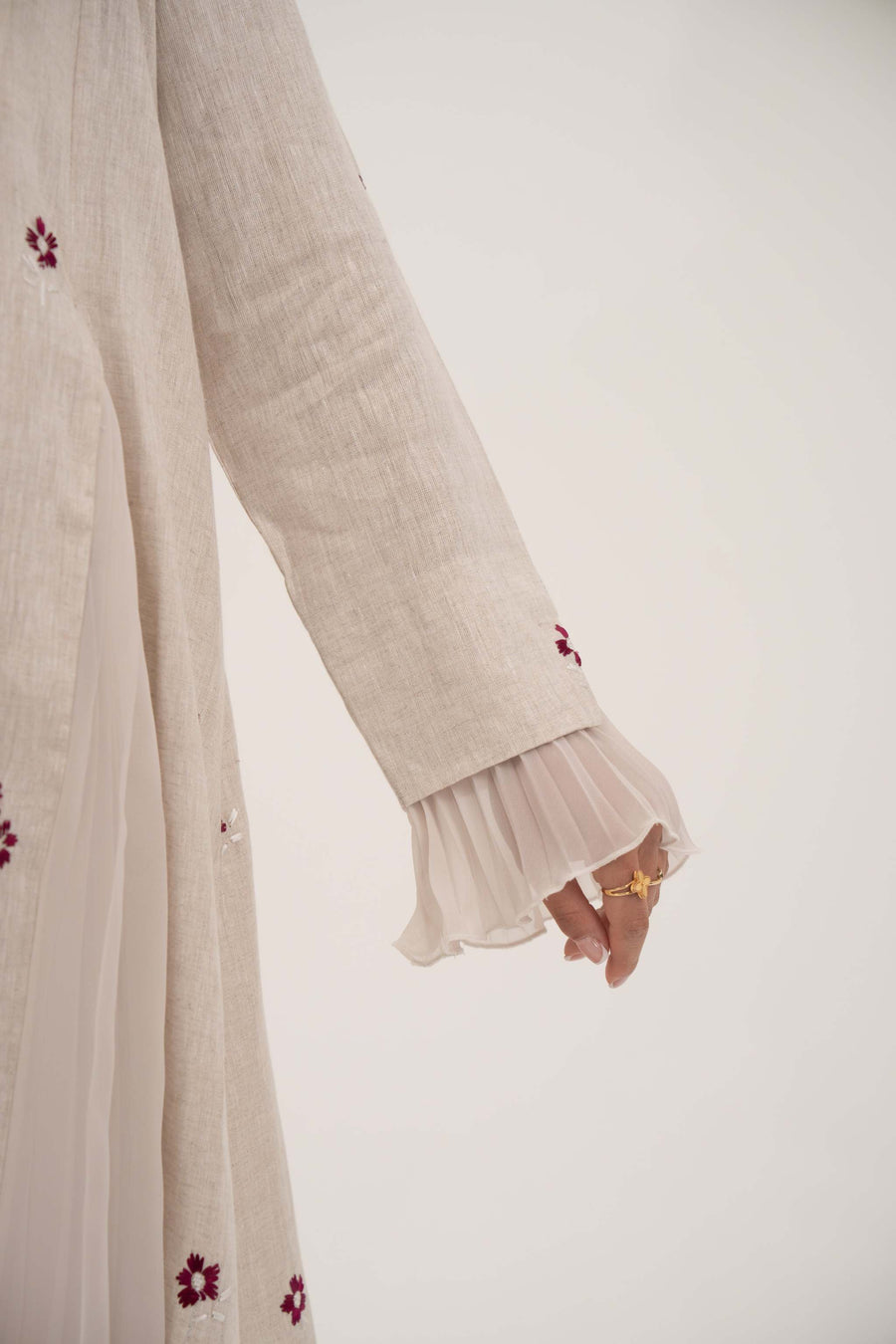 Beige linen abaya with burgundy floral embroidery and soft chiffon pleats on sleeves.