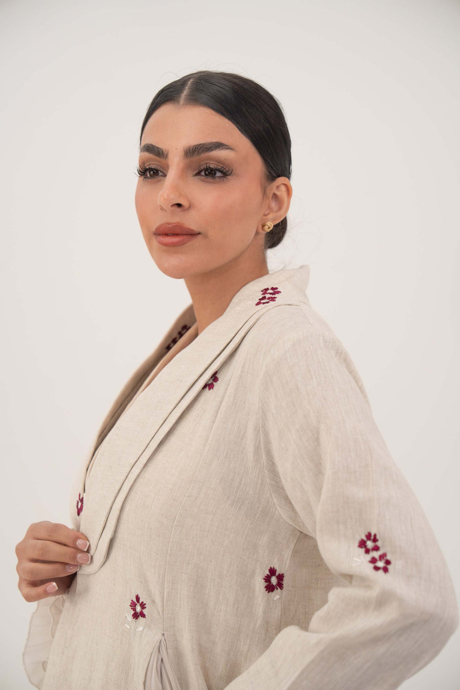 Lightweight beige linen abaya with burgundy floral embroidery and soft chiffon pleats, featuring a shawl collar for an elegant flowing look.