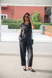 Woman wearing navy-blue Blueberry Pant linen trousers with a relaxed fit and straight cut, paired with a sleeveless black top and sunglasses outdoors