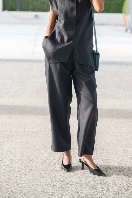 Woman wearing navy-blue Blueberry Pant linen trousers with a relaxed fit and straight cut, paired with a sleeveless black top and sunglasses outdoors