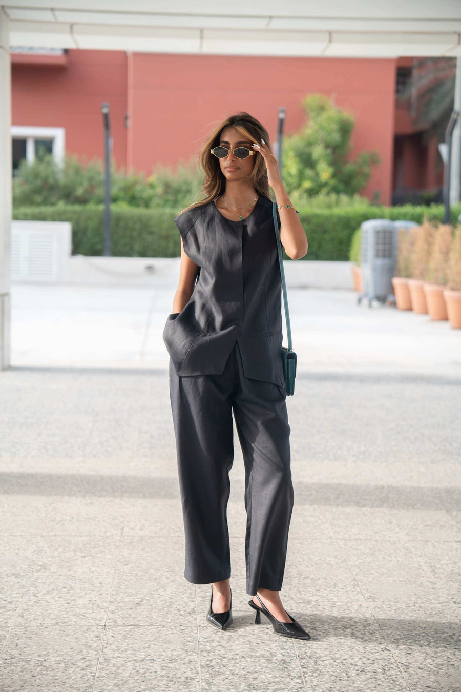 Woman wearing navy-blue Blueberry Pant linen trousers with a relaxed fit and straight cut, paired with a sleeveless black top and sunglasses outdoors
