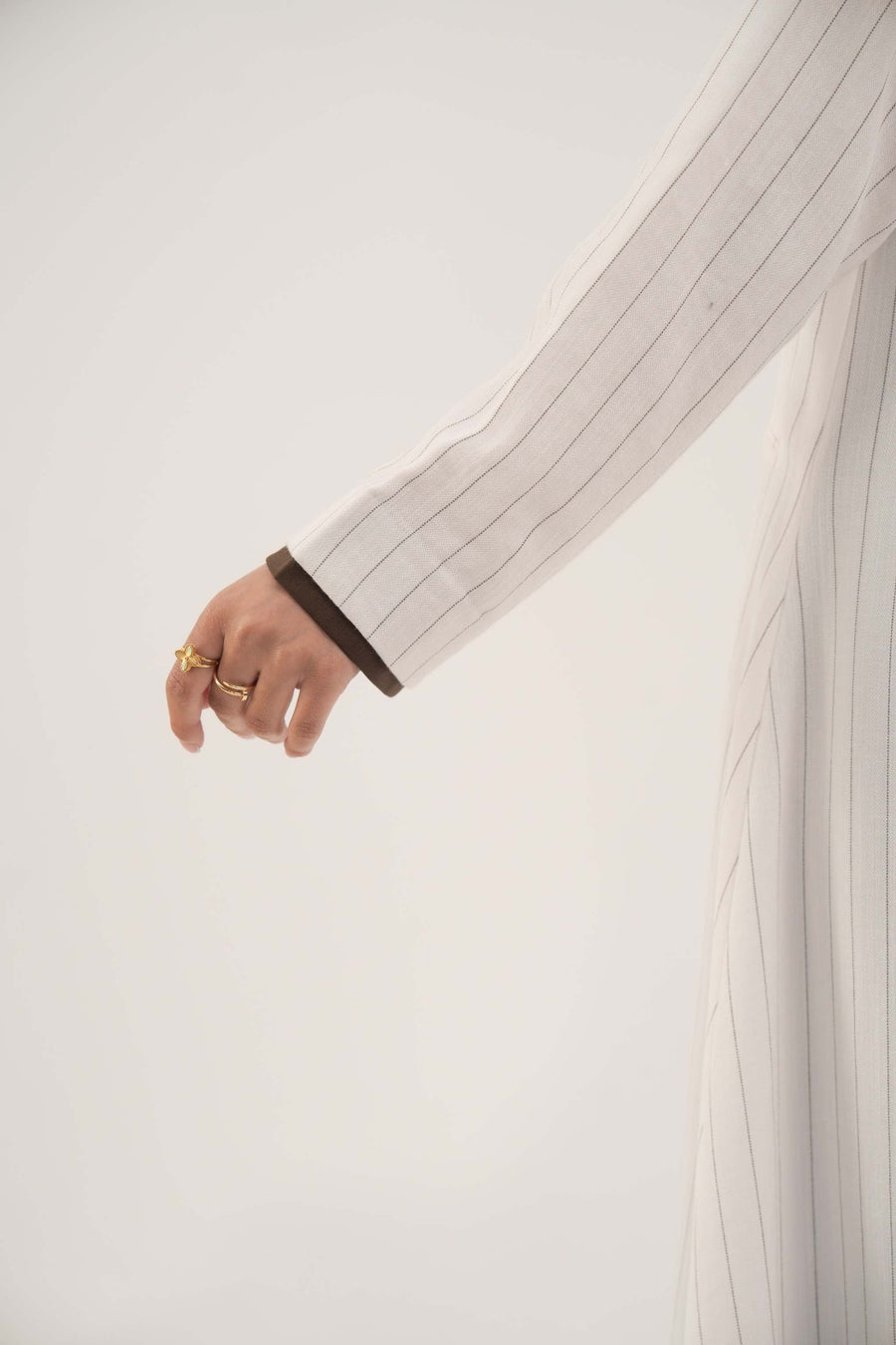 Close-up of a white linen abaya sleeve with grey pinstripes and dark brown inner cuff detailing - Elegant abaya