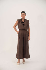 Brown sleeveless linen blouse with soft cowl neckline and structured shoulders, paired with matching wide-leg pants