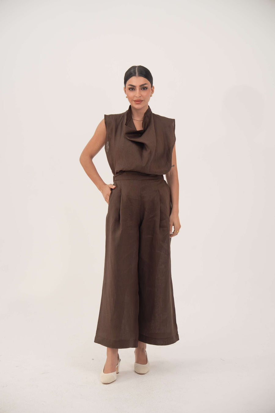 Brown sleeveless linen blouse with soft cowl neckline and structured shoulders, paired with matching wide-leg pants