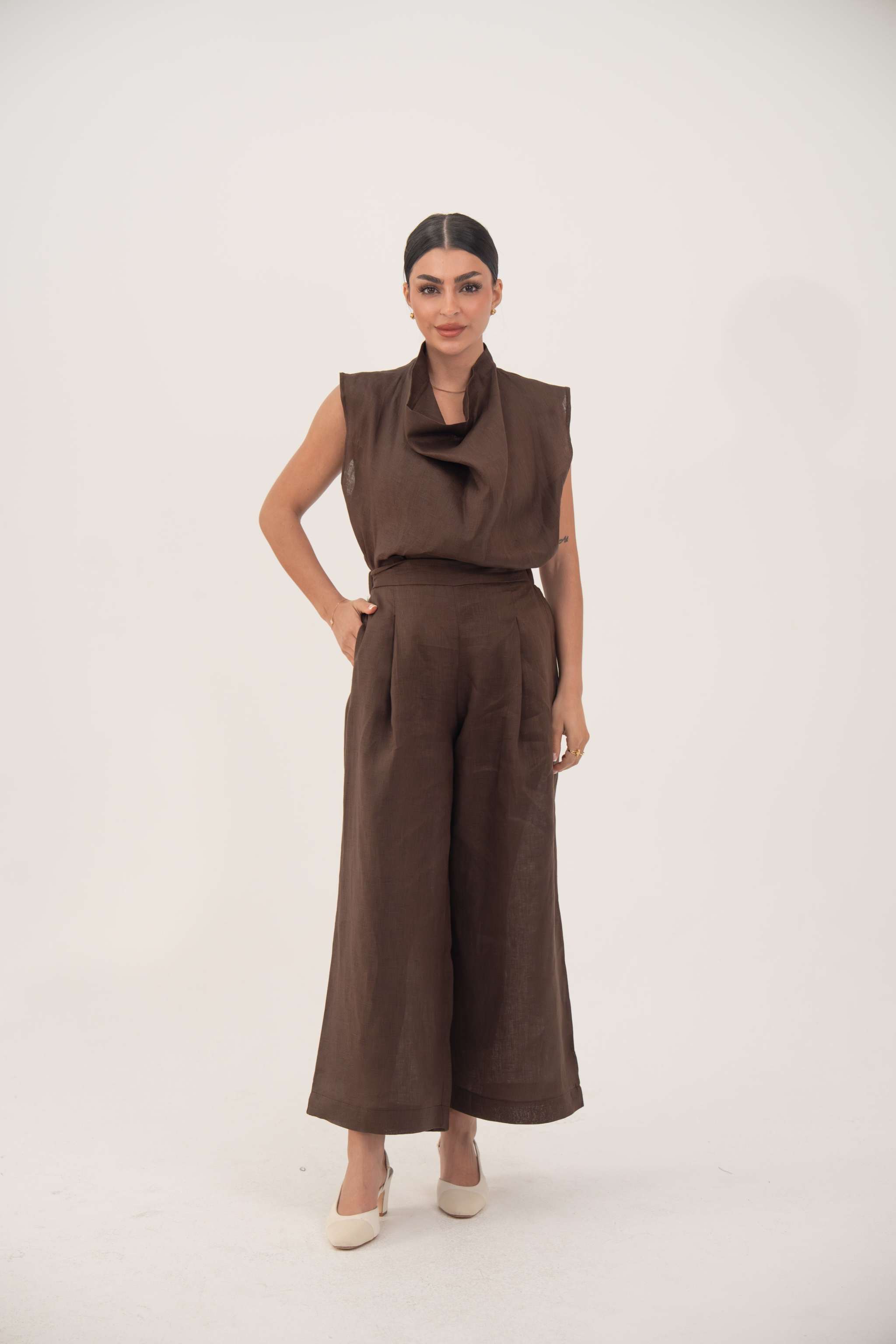 Woman wearing brown linen wide leg pants with pockets and a sleeveless brown top
