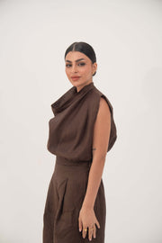 woman wearing sleeveless brown linen blouse with draped neckline and pleats