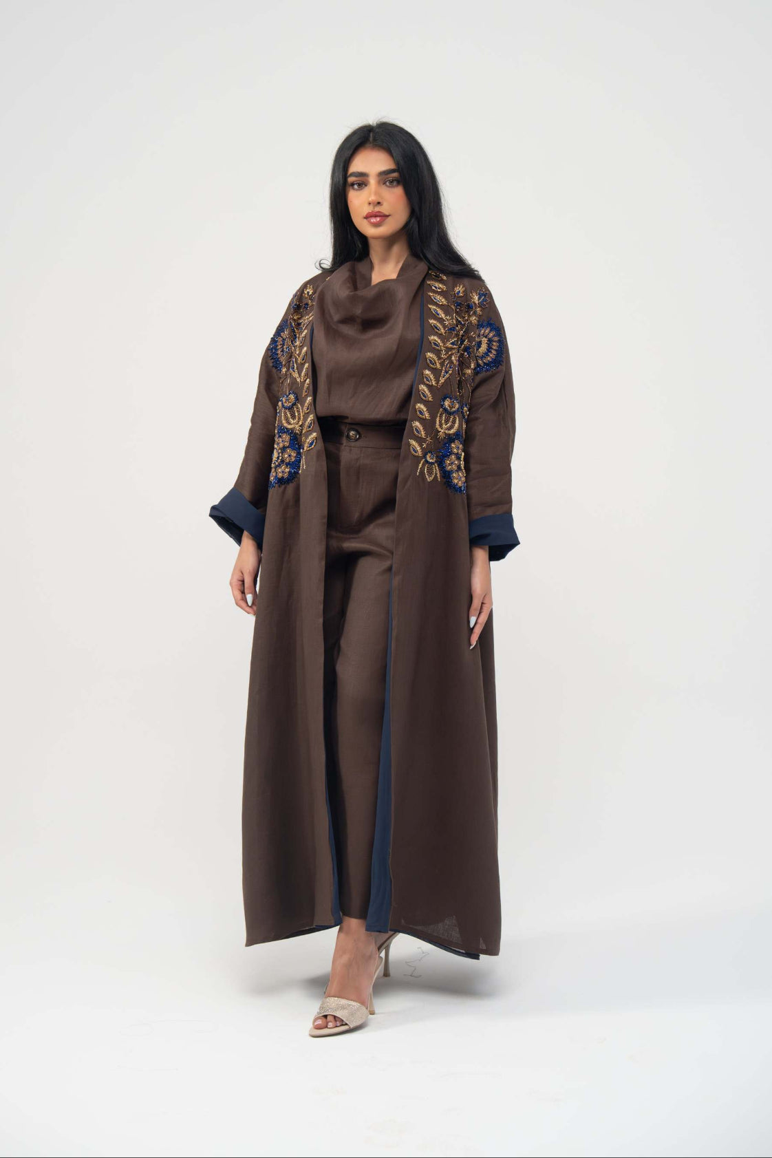 Elegant Azmira bisht abaya in rich brown linen with navy blue chiffon lining and gold embroidery on the upper front.