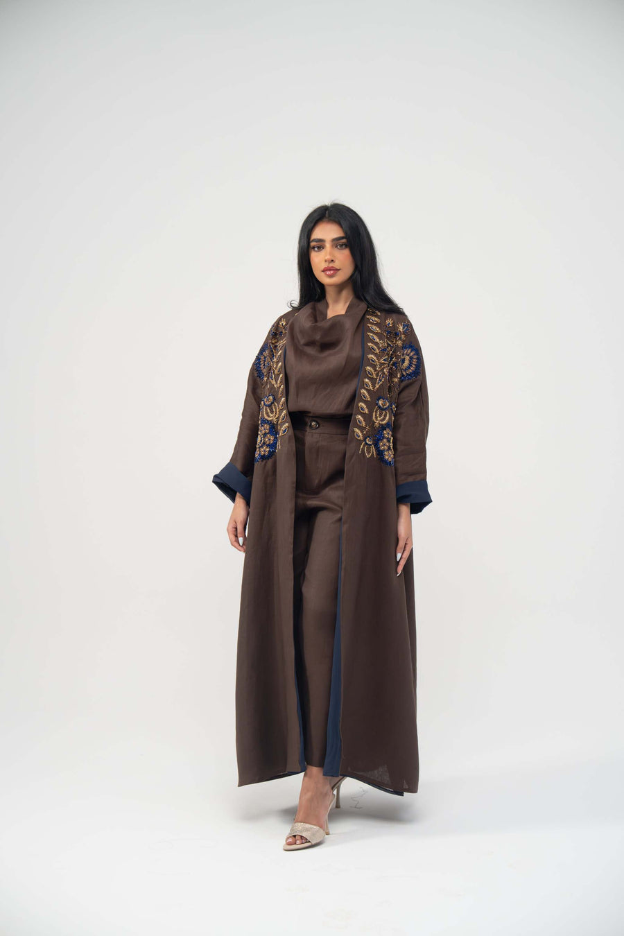 Elegant Azmira bisht abaya in rich brown linen with navy blue chiffon lining and gold embroidery on the upper front.