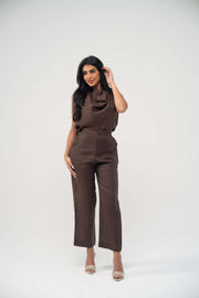 Woman wearing espresso brown sleeveless linen blouse with draped neckline and matching high-waisted pants