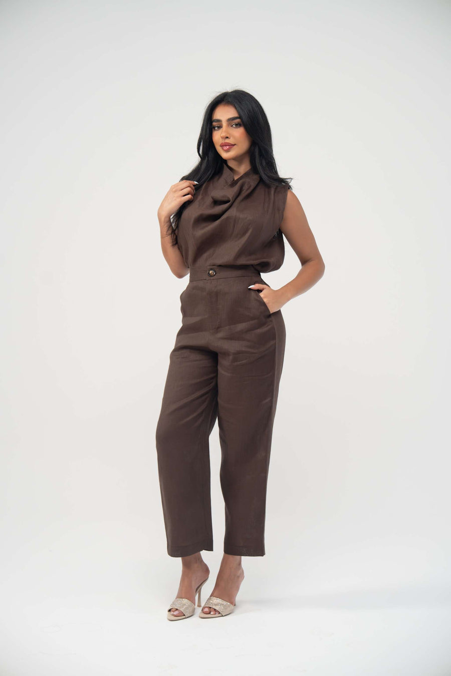 Woman wearing sleeveless warm brown espresso linen blouse with soft draped neckline and light pleats paired with matching pants