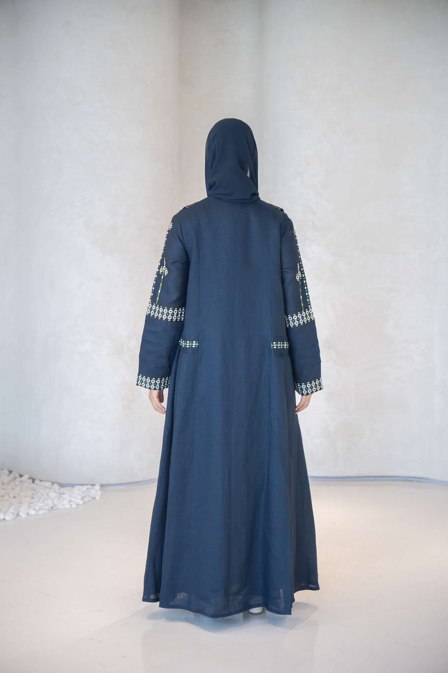 Navy blue breathable lightweight linen abaya with intricate hand-embroidered floral patterns on sleeves and cuffs, featuring a structured notched lapel collar.