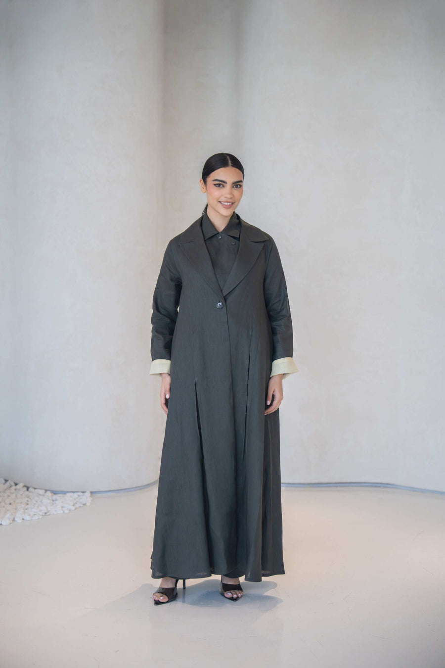Charcoal gray blazer style abaya with classic collar, front buttons, pastel yellow cuff lining, and side pocket in lightweight linen.