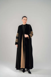 Woman wearing Luxe black abaya with rich velvet, gold hand-embroidery, and chiffon lining