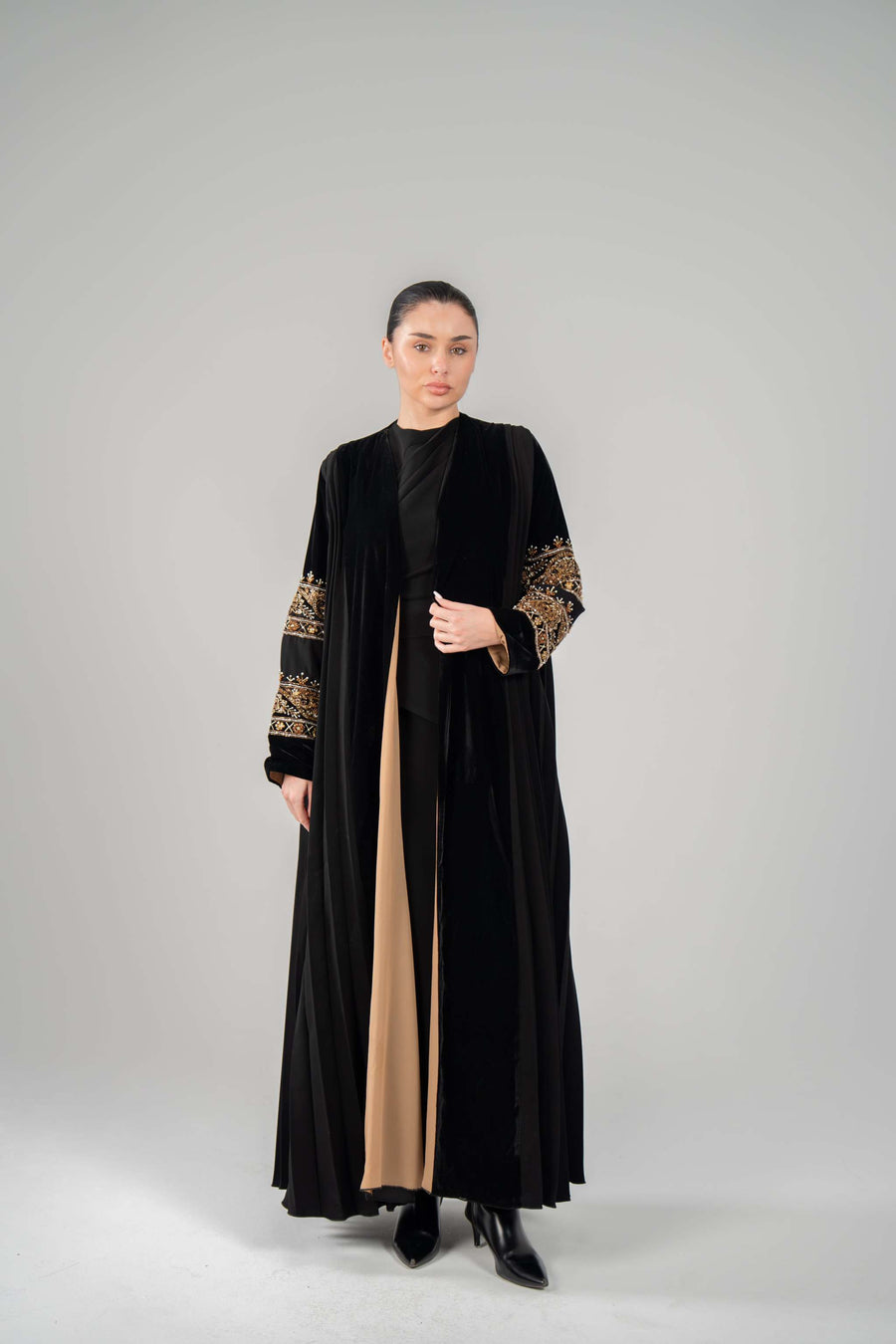 Woman wearing Luxe black abaya with rich velvet, gold hand-embroidery, and chiffon lining