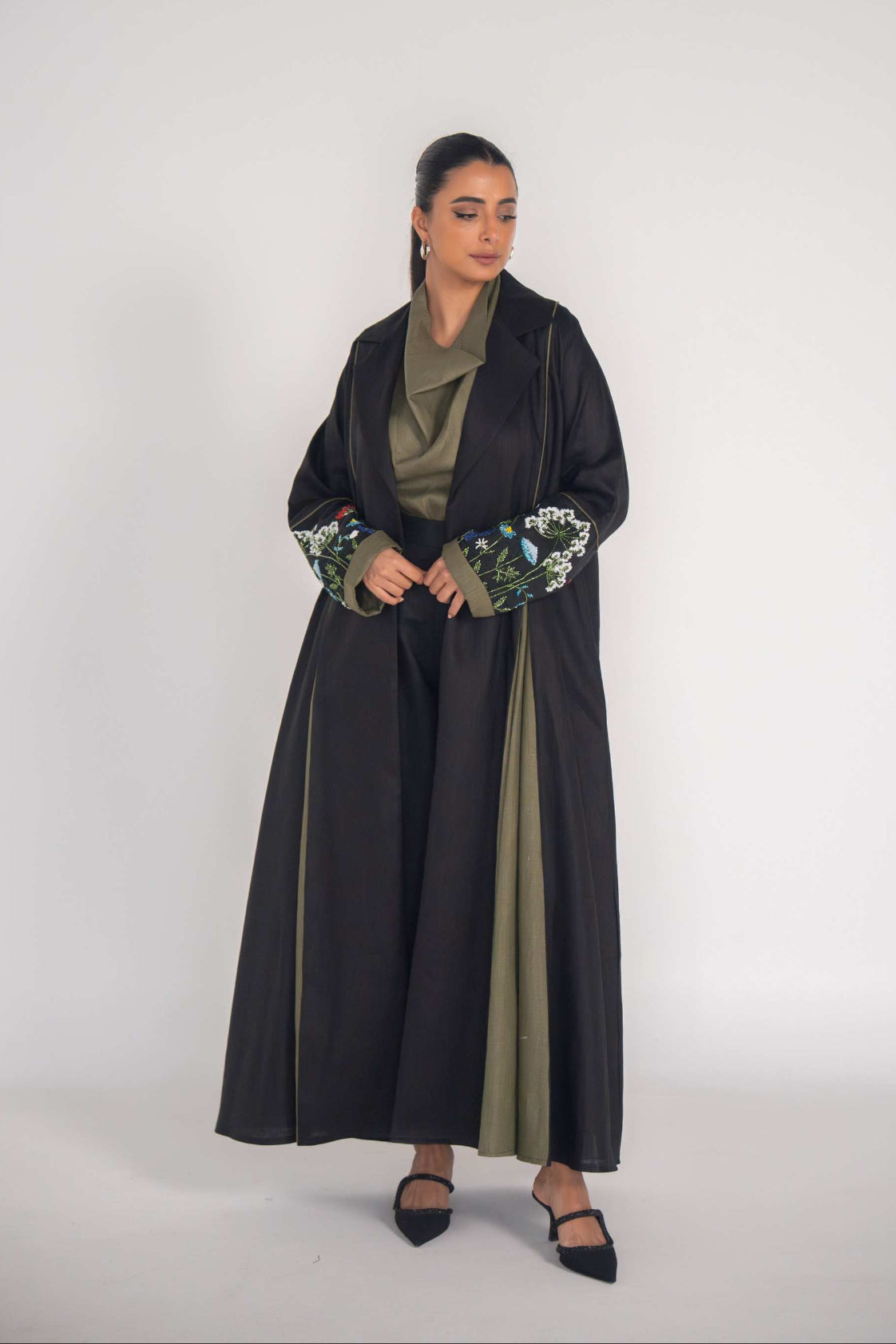 Elegant black graceful abaya with embroidered sleeves and soft pleats over olive green inner dress