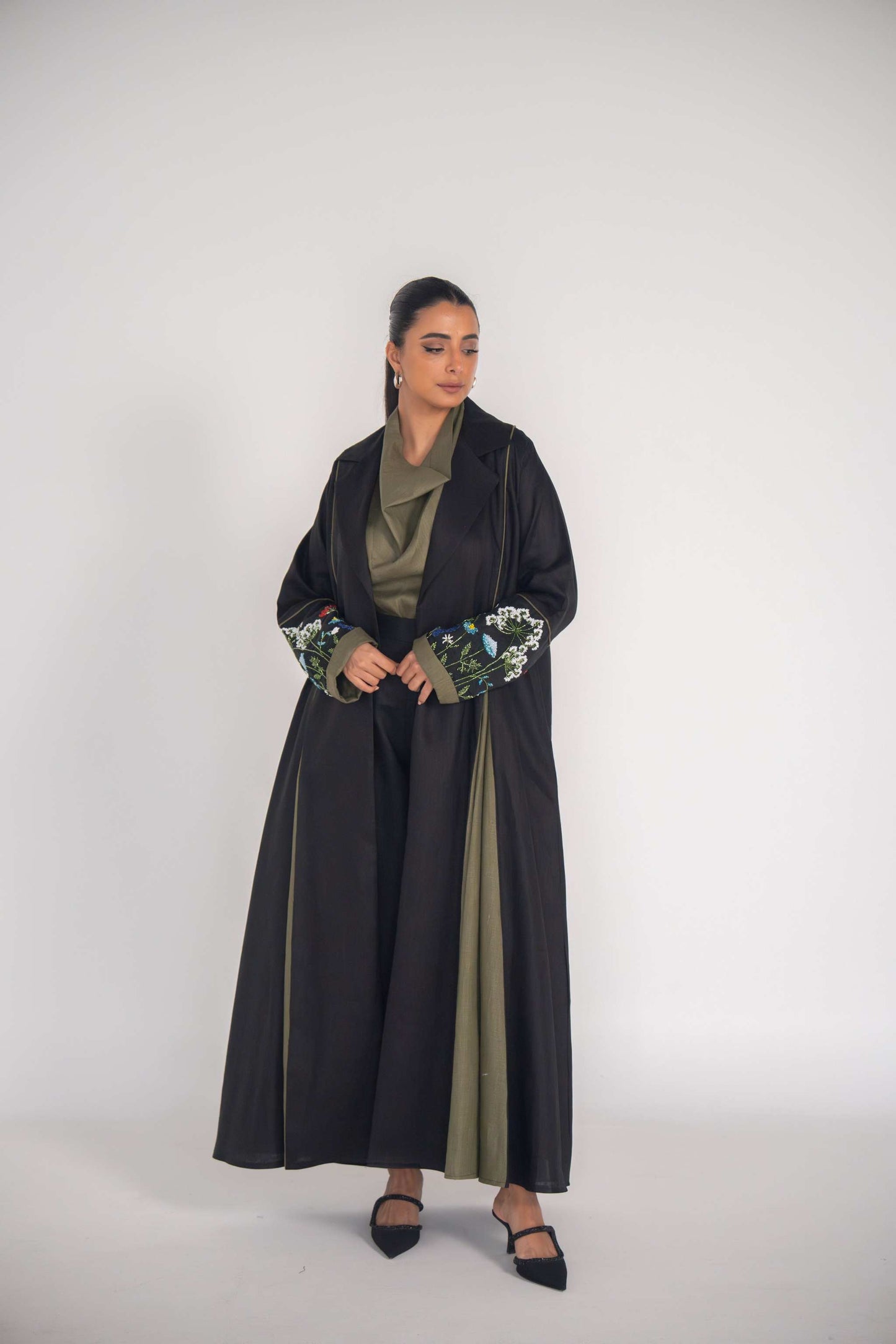 Elegant black graceful abaya with embroidered sleeves and soft pleats over olive green inner dress