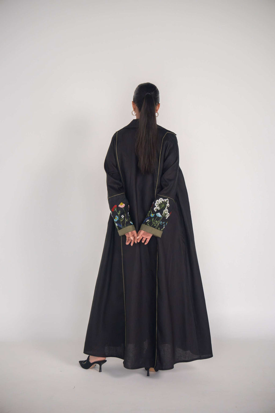 back view of black abaya with embroidered sleeves and olive green box pleats