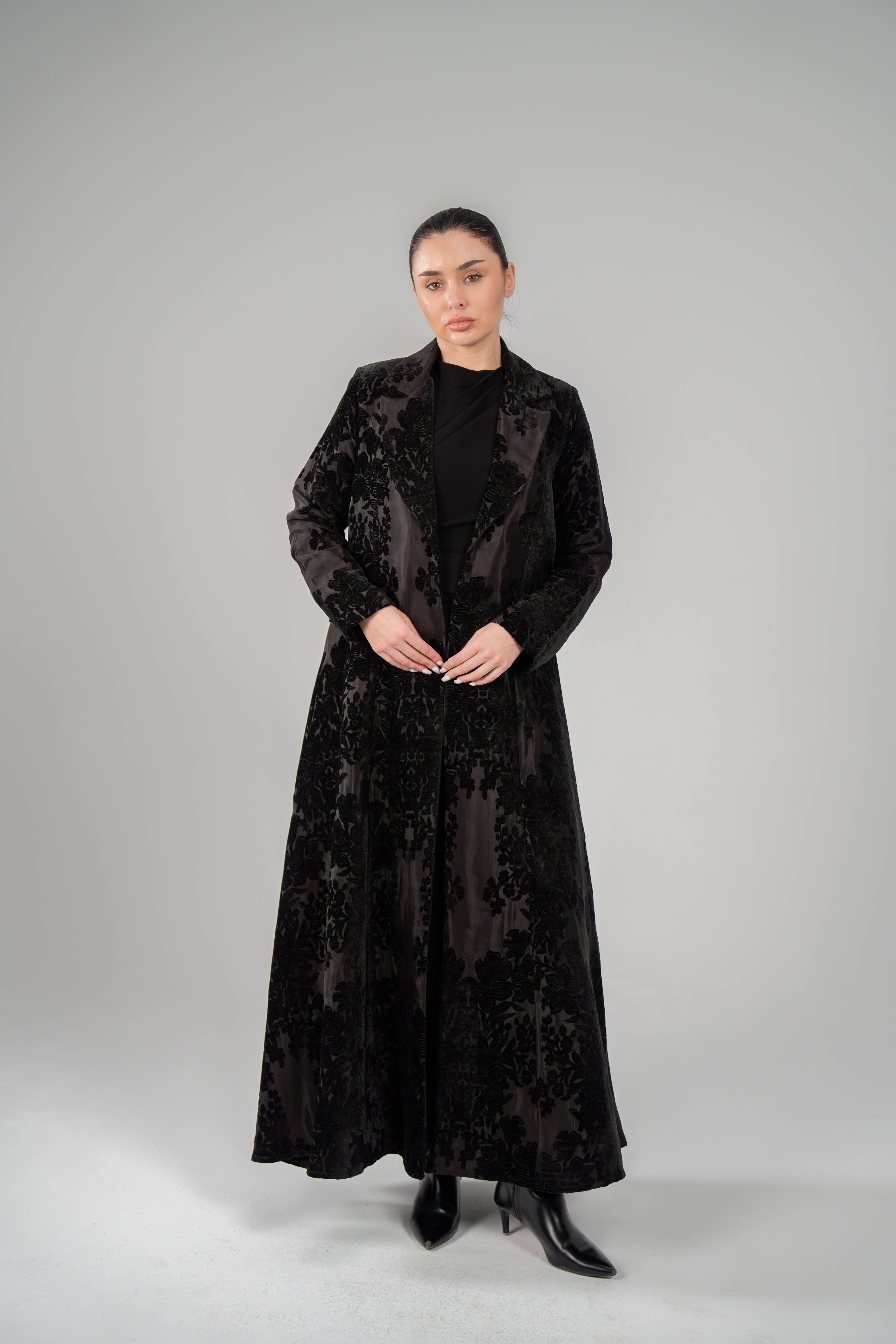 Woman wearing Black Jaguar velvet floral textured long blazer abaya with tailored lapels and sleek silhouette