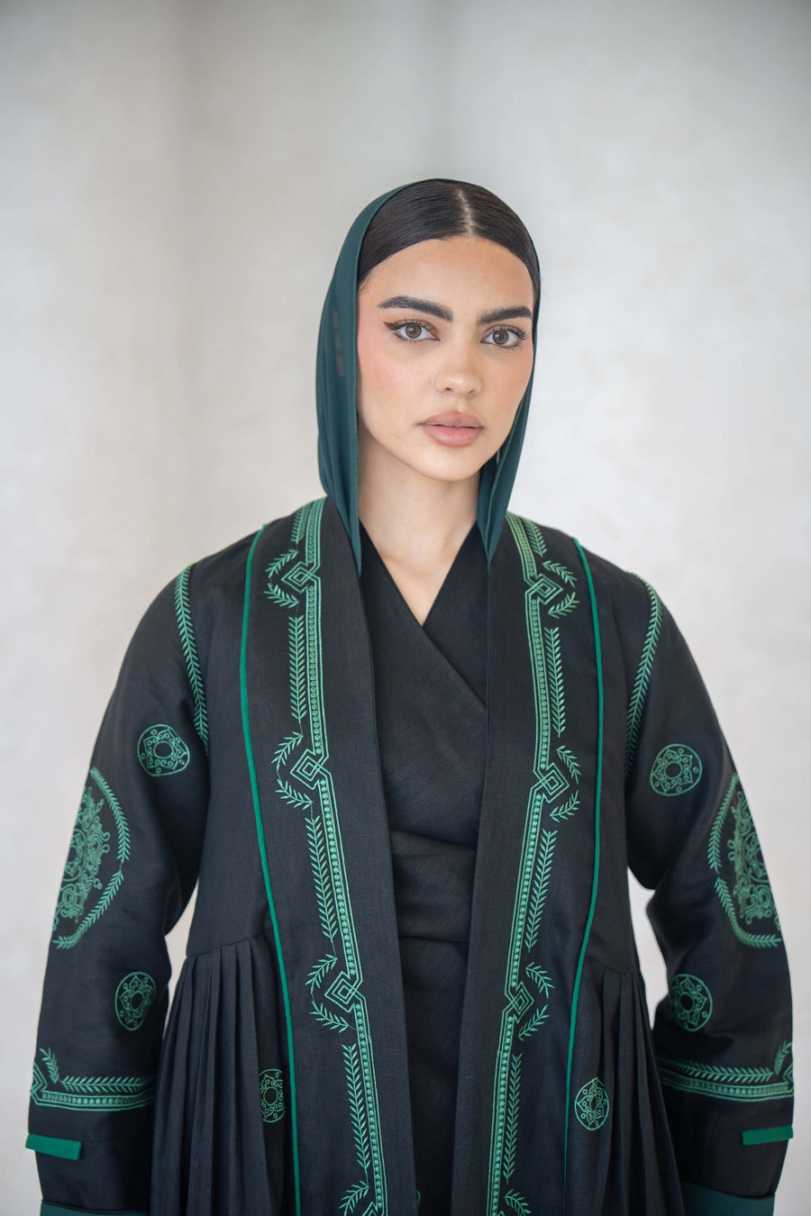 Black Zamurd abaya with green geometric embroidery on front, sleeves, and shoulders, lightweight linen with soft chiffon lining.