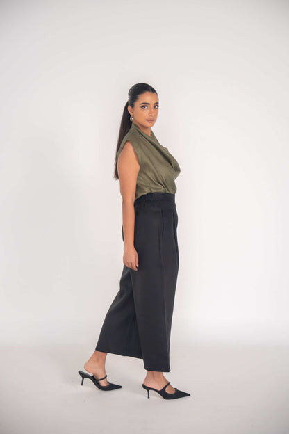 Woman wearing black Raya Pant with straight-leg cut and olive sleeveless top in studio setting