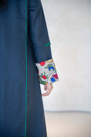Deep navy linen abaya with emerald green piping and multicolor embroidered cuffs, featuring a modern open-front design and tailored silhouette.