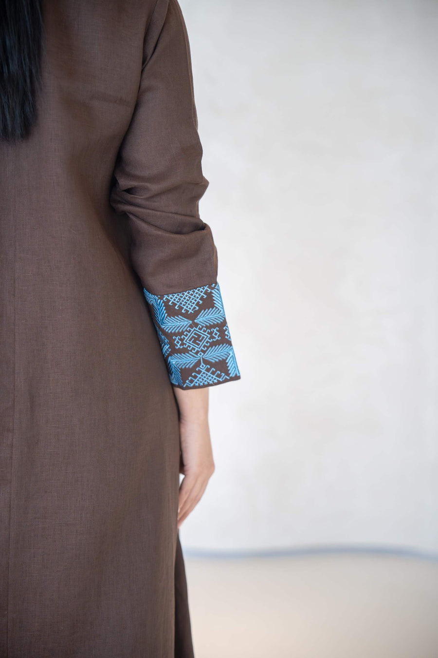 Close-up of brown abaya sleeve with vertical blue embroidery and faux flap pocket detail abaya in a calm brown