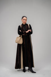 Elegant dark velvet abaya with machine embroidery and crinkled fabric details, worn by woman with beige handbag and black boots